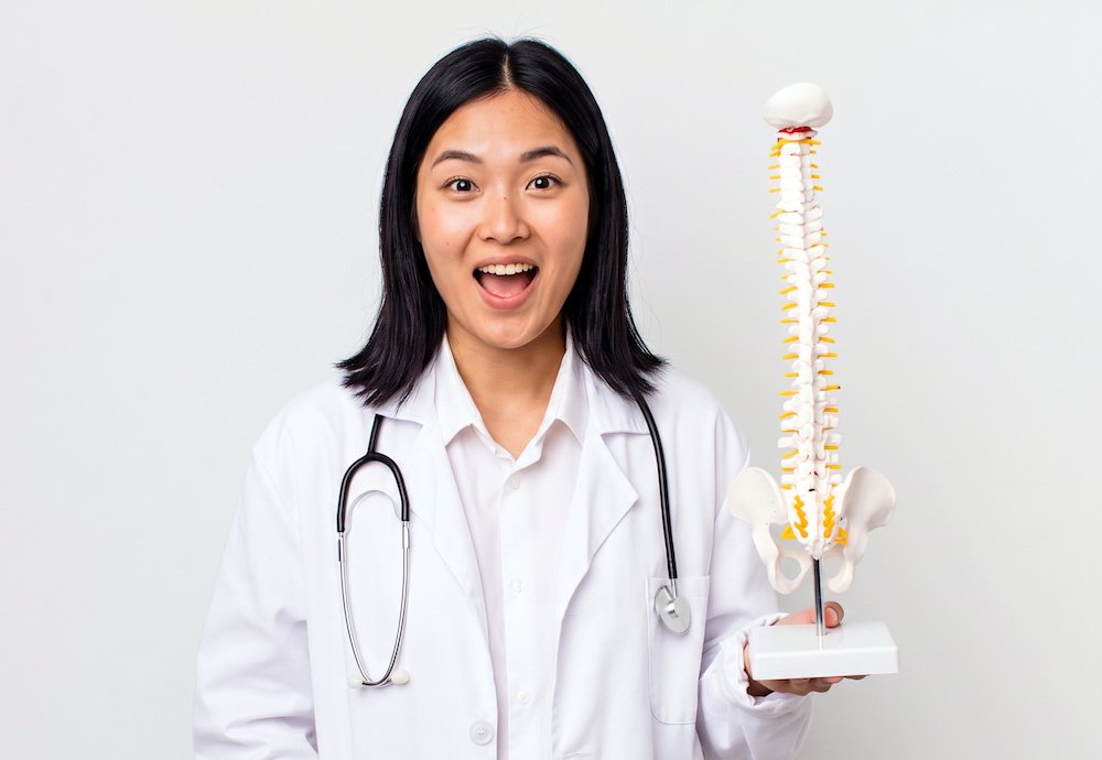女醫生手持脊椎骨骼模型,說明補充希臘乳酪豐富的鈣質與礦物質有助維持骨骼健康